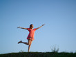 Foto: The young woman in an orange dress, costs on a green hill The young woman in an orange dress, costs on a green hill