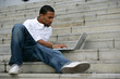 black man working on laptop in stairs