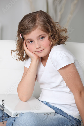 Photo: Bored little girl sat with laptop Bored little girl sat with laptop