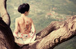 Woman with snake tattoo sitting on tree branch