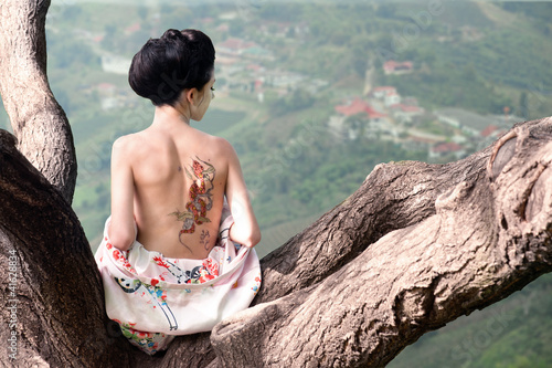 Photo: Woman with snake tattoo sitting on tree branch (Orig) Woman with snake tattoo sitting on tree branch (Orig)