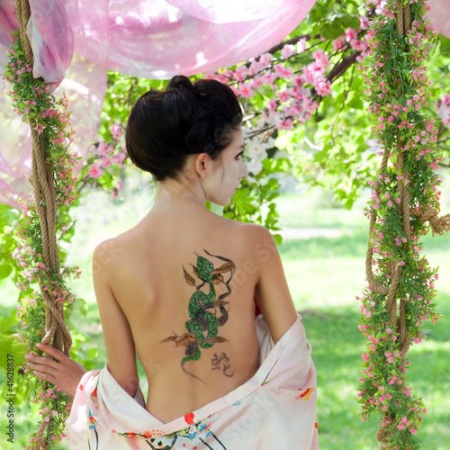 Photo: Asian style portrait of woman with snake tattoo on her back Asian style portrait of woman with snake tattoo on her back