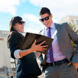 Business couple outdoors with catalog.