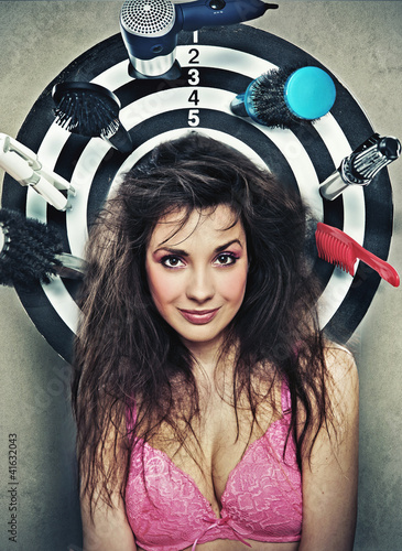 Foto: Cute brunette posing as a target with hairdresser's instruments Cute brunette posing as a target with hairdresser's instruments