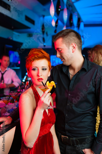 Photo: Young couple in bar or club drinking cocktails Young couple in bar or club drinking cocktails