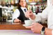 Barista mit Gast in seinem Cafe oder Coffeeshop