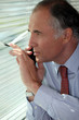 Senior businessman looking through blinds
