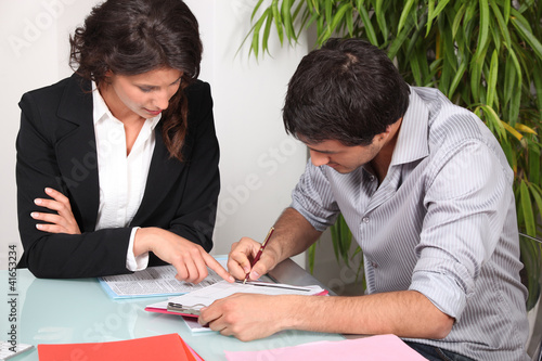 Photo: Businesswoman helping her client fill in paperwork Businesswoman helping her client fill in paperwork