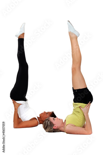 Photo: Young women performing shoulder stands Young women performing shoulder stands