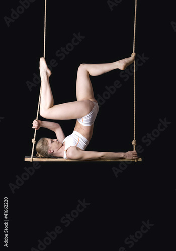 Foto: Young woman gymnast on black background Young woman gymnast on black background