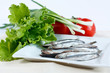 Anchovy fish on a plate with lettuce, green onions and tomatoes