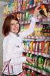Photo: Pretty woman buyer in grocery shop at shelves with products Pretty woman buyer in grocery shop at shelves with products