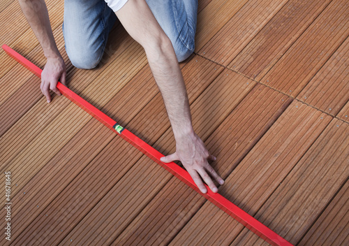 Photo: Man using spirit level on the floor Man using spirit level on the floor