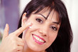 Smiling adult female applying face moisturizer