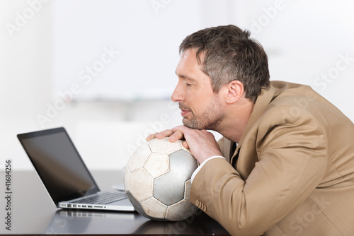 Foto: mann mit fußball vor dem laptop mann mit fußball vor dem laptop