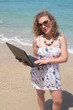 Curly hair young woman with her laptop at the beach
