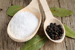 Salt and pepper in spoon on wooden background