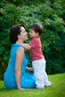 Two years old boy hugs his young mom in park