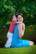 Two years old boy hugs his young mom in park