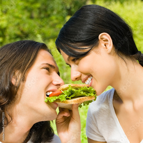 Photo: Young couple eating together outdoors Young couple eating together outdoors