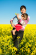 Mother carried her child through rapeseed field Mother carried her child through rapeseed field
