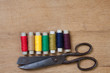 Old scissors and color threads on wood background