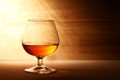 Glass of cognac over wooden surface