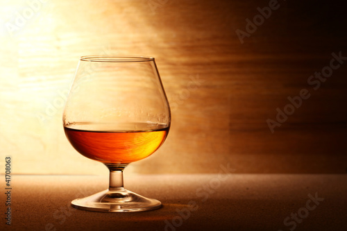 Photo: Glass of cognac over wooden surface Glass of cognac over wooden surface