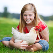 girl sitting on a meadow with her chicken