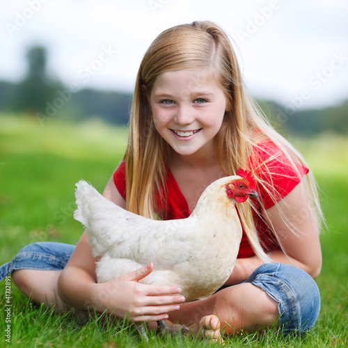 Photo: girl sitting on a meadow with her chicken girl sitting on a meadow with her chicken