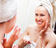 woman looking in mirror and applying cream