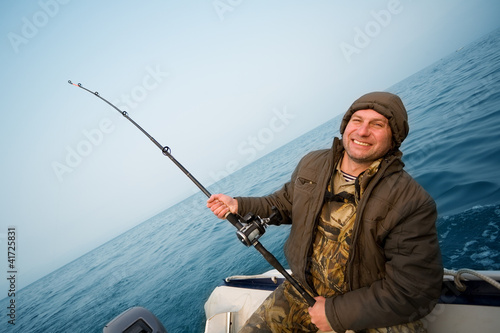 Photo: Fisher holds trolling rod. Focus on the right hand. Fisher holds trolling rod. Focus on the right hand.