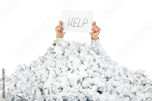Photo: Person under crumpled pile of papers with a help sign / isolated Person under crumpled pile of papers with a help sign / isolated