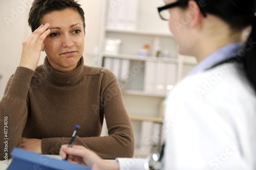 Photo: Woman suffering from migraine and doctor Woman suffering from migraine and doctor
