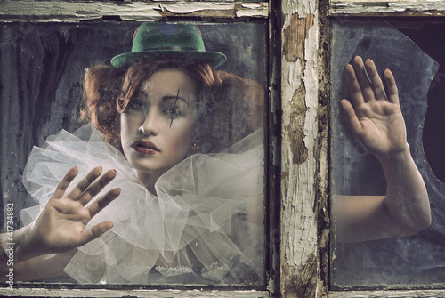 Foto: A lonely sad pierrot woman behind the glass A lonely sad pierrot woman behind the glass