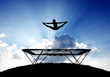 silhouette of female gymnast on trampoline in front of clouds