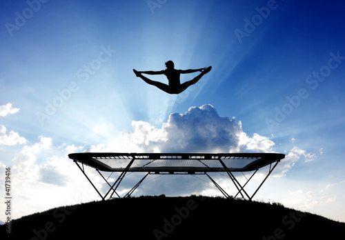 Illustration: silhouette of female gymnast on trampoline in front of clouds silhouette of female gymnast on trampoline in front of clouds
