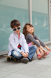 Brother an sister sitting in front of the wall