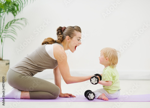 Photo: Baby helping mother lifting dumb-bells Baby helping mother lifting dumb-bells
