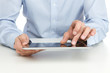Close up of young adult using digital tablet by the desk