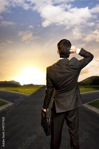 Photo: young businessman in front of a crossroad young businessman in front of a crossroad