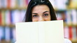 woman hides behind a book, cover is blank