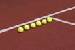Line of six yellow tennis balls on court Line of six yellow tennis balls on court