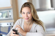 Young woman using smartphone at home with earphones Young woman using smartphone at home with earphones