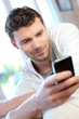 Young man using mobile phone to send short message