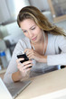 Young woman using smartphone at home with earphones Young woman using smartphone at home with earphones
