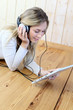 Young modern girl listening to music with electronic tablet