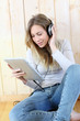 Young modern girl listening to music with electronic tablet