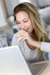 Woman checking email on laptop computer while drinking coffee