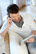 Man talking on the phone while using tablet Man talking on the phone while using tablet